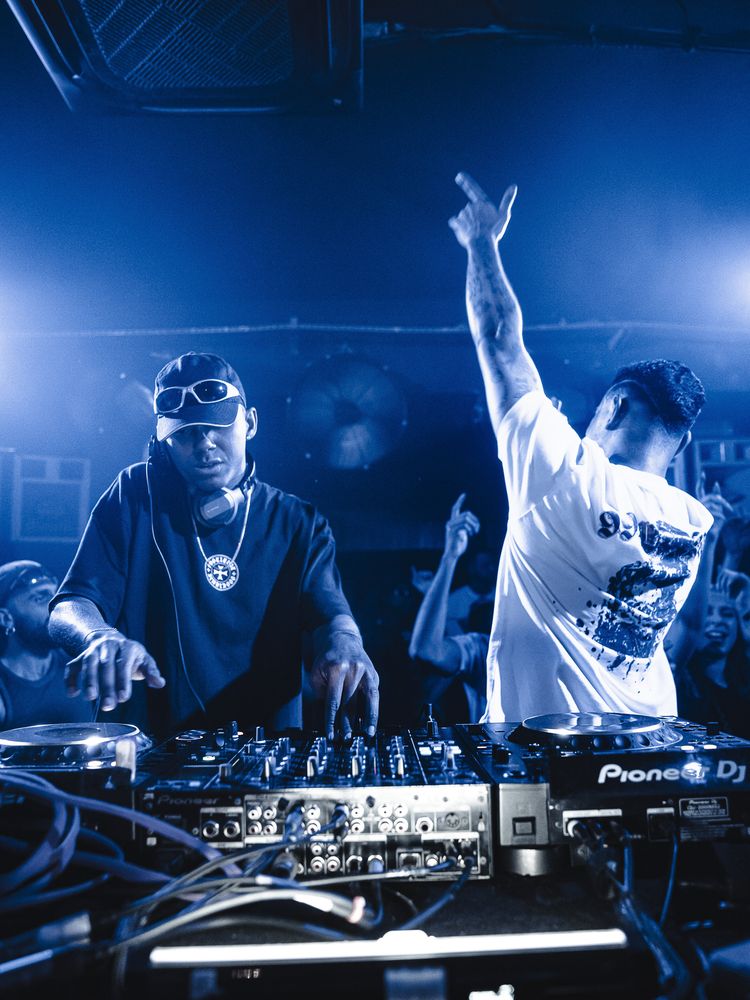 Dois DJs nos decks em luz azul